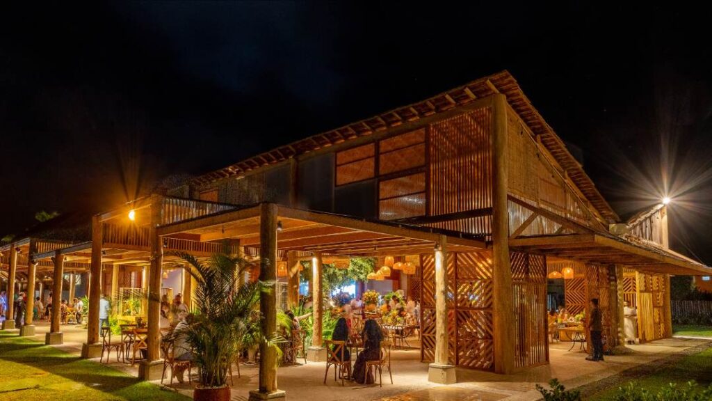Casa de festa da Bisutti em estilo rústico-chique à noite, com estrutura de madeira, iluminação aconchegante e convidados reunidos em ambiente sofisticado.