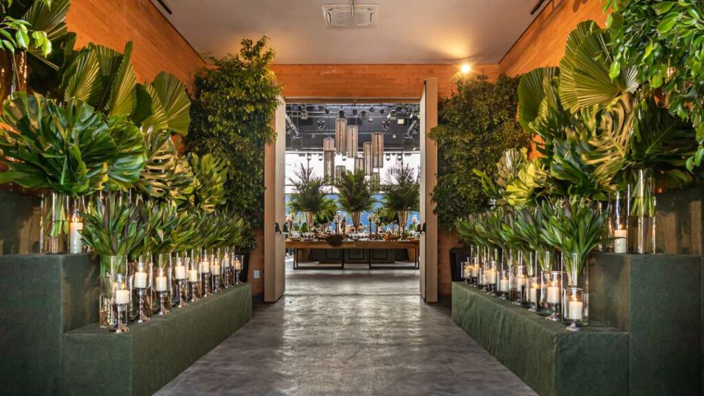 Ambiente sofisticado de casa de festa, com folhagens, velas e buffet, ideal para eventos corporativos com elegância e estrutura.
