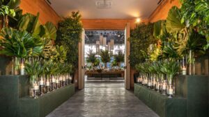 Ambiente sofisticado de casa de festa, com folhagens, velas e buffet, ideal para eventos corporativos com elegância e estrutura.