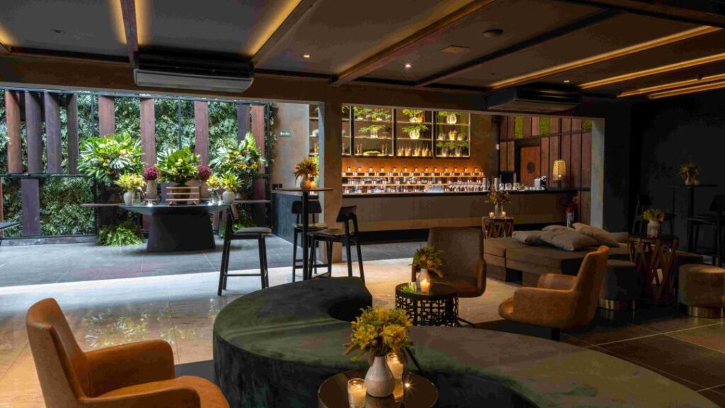  sofisticada casa de festa com atmosfera aconchegante e contemporânea. O espaço conta com um elegante bar iluminado ao fundo, lounges com poltronas e sofás em tons neutros